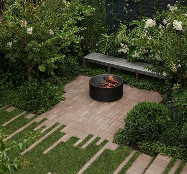 Patio with fire pit and wooden bench.