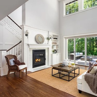 A wood-burning fireplace insert in a large living room just off a staircase
