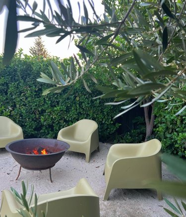 Fire pit with green plastic chairs in garden.