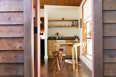 kitchenette with light wood cabinets, black counters, two shelves, a mini fridge, and small stovetop