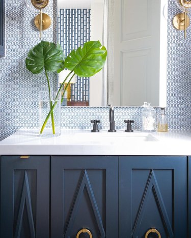 contemporary coastal bathroom with navy penny tile backsplash, navy cabinet and brass accents