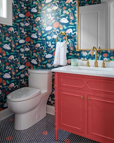 powder room with navy adn red floral flamingo wallpaper, coral red lacquer vanity and navy and red penny tile floor