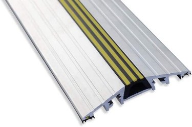 An aluminum garage door threshold with three yellow stripes in the middle
