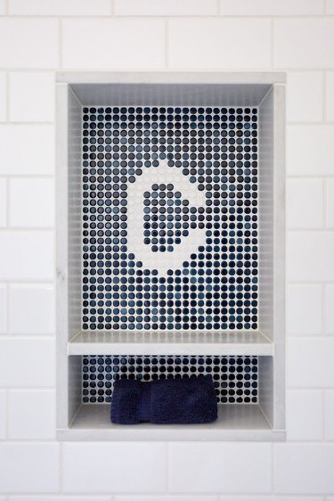 white tile bathroom niche with navy penny tile monogram detail and navy towel