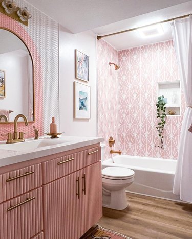 pink and white bathroom with sunburst shower tile and pink and white arch patterned penny tile backsplash