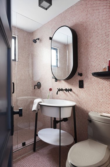 pink penny tile bathroom with black retro accents and walk-in shower