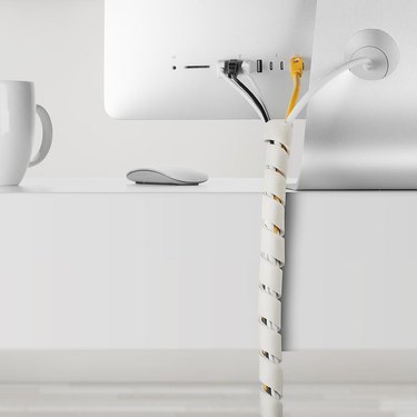 white cable Slinky behind desk containing several cords