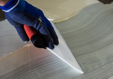 person applying adhesive during laying of linoleum floor