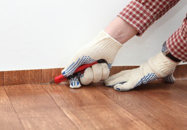 cutting off excess linoleum from wall