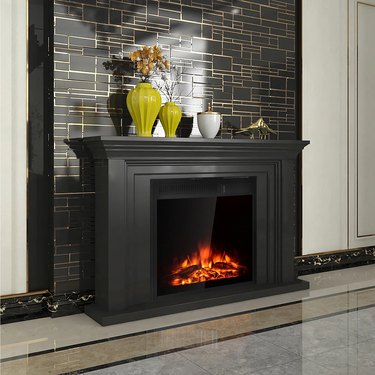 A black electric fireplace that's lit up; a black geometric wall is behind it