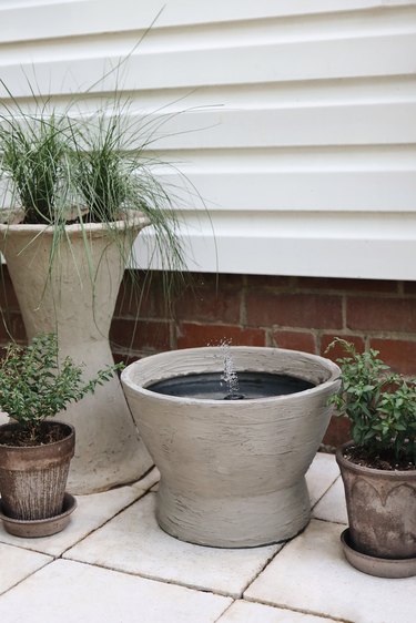DIY concrete water fountain on patio with planters