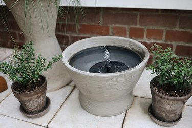 IKEA hack concrete water fountain on patio with planters