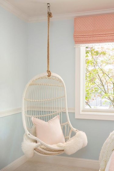 bedroom with two shades of blue and hanging rattan chair