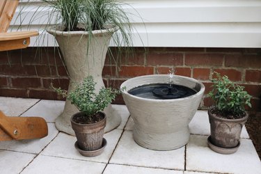 A concrete fountain on a patio next to other concrete planters