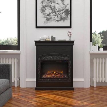 A black freestanding electric fireplace on a herringbone patterned wood floor
