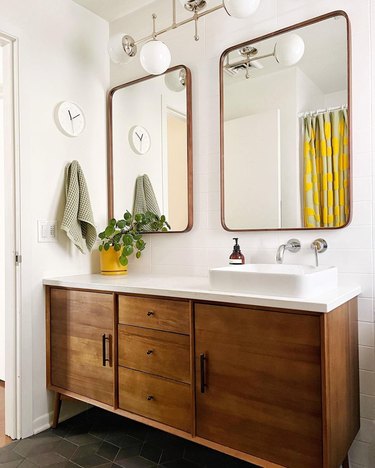midcentury bathroom with warm wood vanity, white vessel sink, and vintage-inspired light fixture