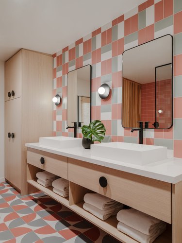 midcentury bathroom with pink, gray, and white geometric wall and floor tiles