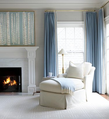 Living room with gray walls, white fireplace and sky blue curtains.