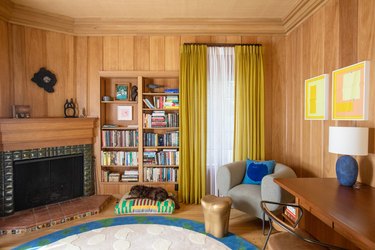 library walls clad in wood paneling with yellow curtains