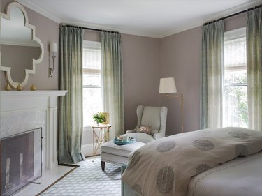 Bedroom with gray walls, fireplace, and sheer sage green curtains