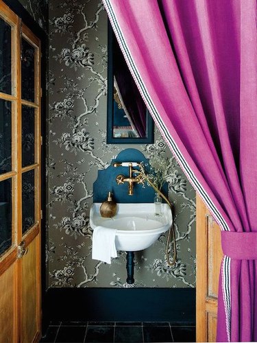 Bathroom with gray patterned wallpaper and a magenta curtain.