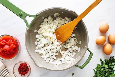Green pan with onions and wooden spatula