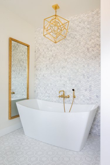 midcentury and contemporary bathroom in gray, white, and brass with hex tile floor and broken chevron wall tile