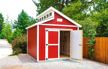 A modern, red Tuff Shed on a gravel patio