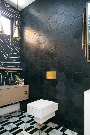 midcentury and contemporary bathroom with matte black hexagon tile wall, black and white abstract wallpaper, and geometric tile floor