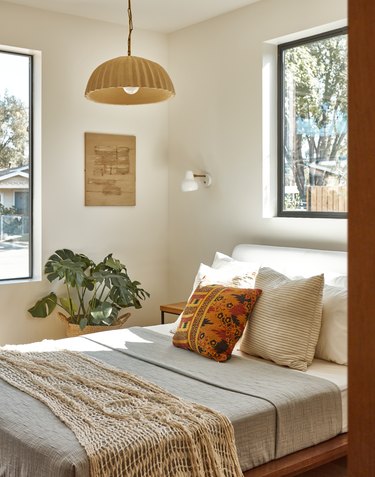 guest room with hanging light fixture, a plant, and two windows
