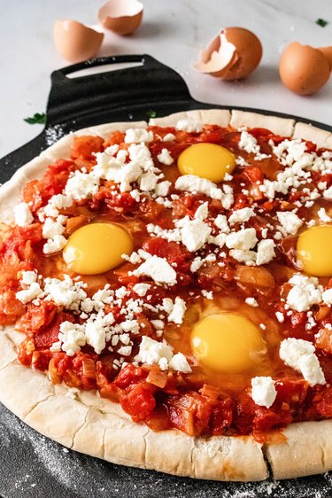 Shakshuka pizza with raw eggs before baking