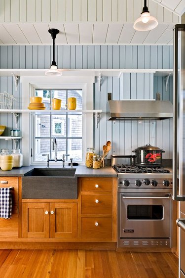 Kitchen with blue shiplap walls, oak cabinets and open shelving.