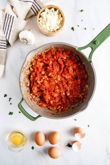 Tomato sauce in a green skillet on a white background
