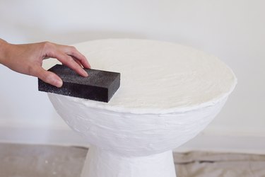 Sanding rough spots on dried plaster with a sanding sponge