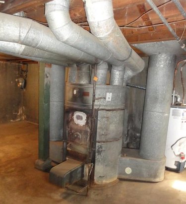 An outdated gravity furnace with duct work coming out of it