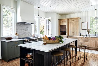 kitchen with oak and green cabinets, black island, and white walls