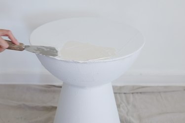 Applying first coat of plaster to table with a putty knife