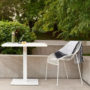 simple white desk and chair outside on concrete patio