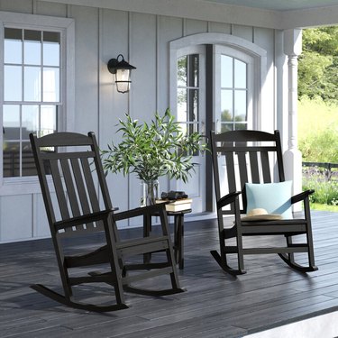 Two black outdoor rocking chairs on porch of white house
