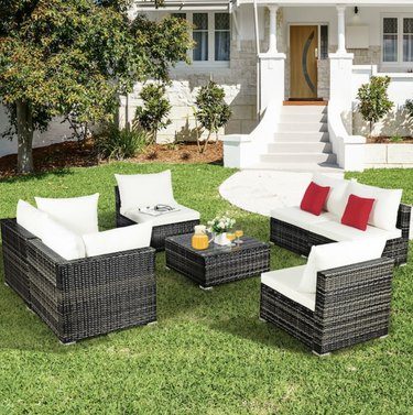 Brown outdoor furniture with white cushions on grass in front yard