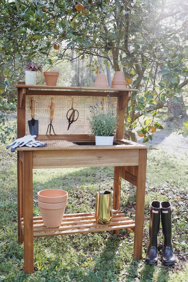 DIY cane webbing potting bench with garden tools and terra cotta pots