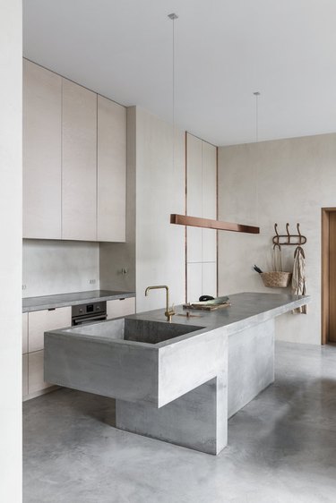 Concrete kitchen island sink with matching concrete floor and modern fixtures