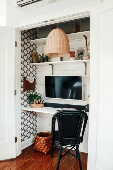 white closet office with woven pendant light hanging above, black desk chair