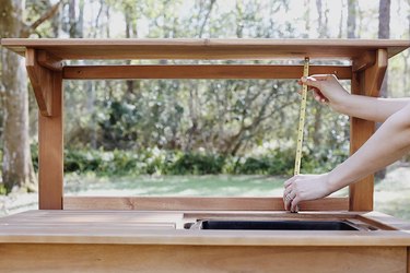 Measuring the opening on the potting bench with tape measure