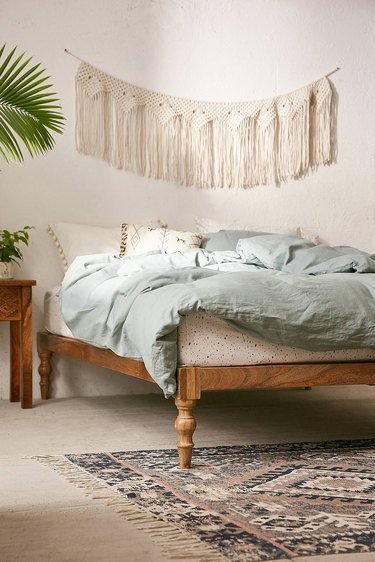 platform bed with wood turned legs and macrame wall hanging