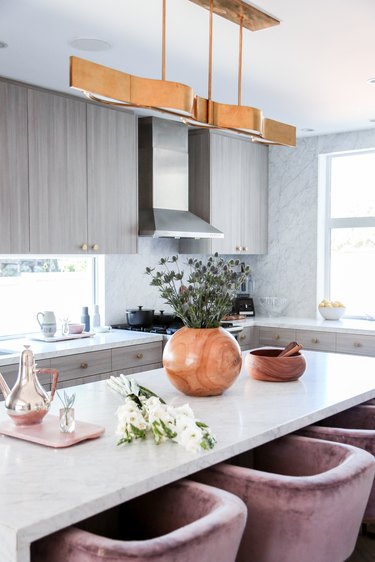 kitchen island with lighting fixture and light pink chairs