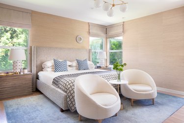 bedroom with light walls and two end chairs near a table