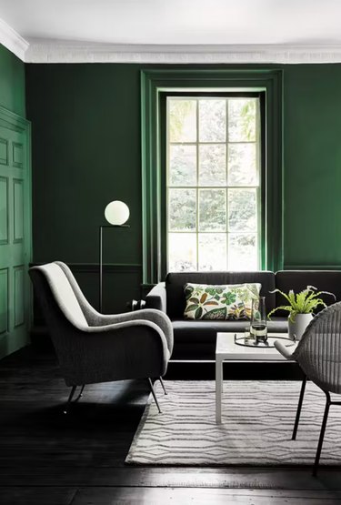 Living room with forest green walls, gray furniture, rug, coffee table.