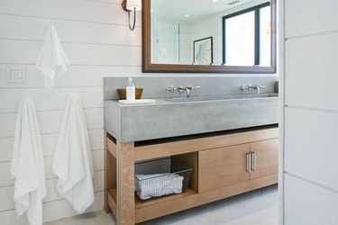 Bathroom with concrete sink, white shiplap walls.