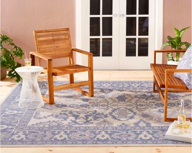 outdoor space with white door, wood chairs, and light blue patterned rug